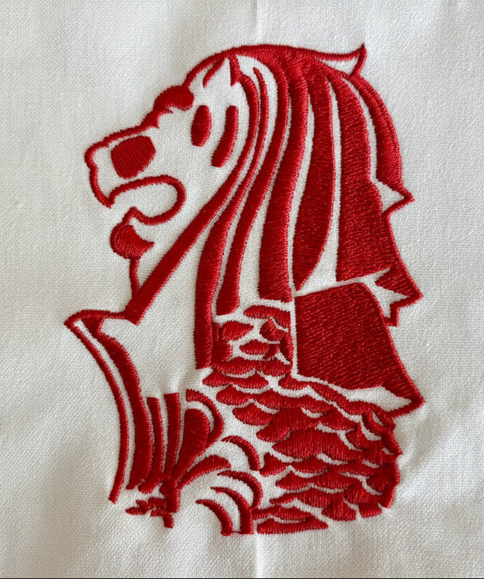 Red embroidered Singapore Merlion design on a white cotton tea towel