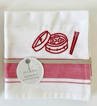 White towel with red design and tag labeled 'Zest of Asia' on a white background