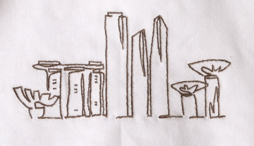 Embroidered Singapore skyline in beige / golden colour, on a white tea towel in cotton. Singapore gift